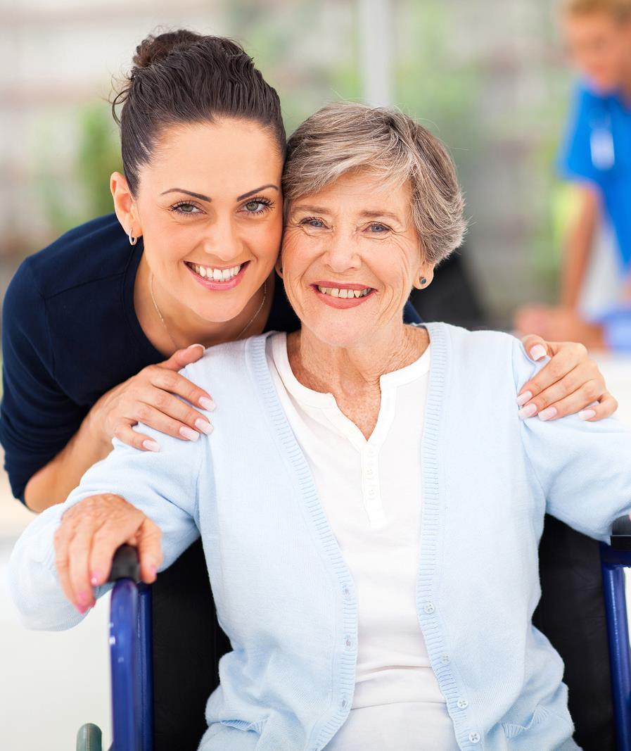 En helsefagarbeider holder rundt en eldre kvinne. Begge smiler.